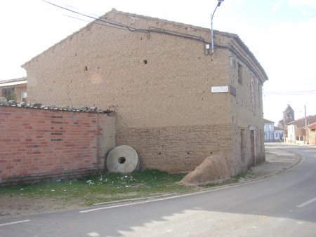 Casa de adobe con una piedra de molino.